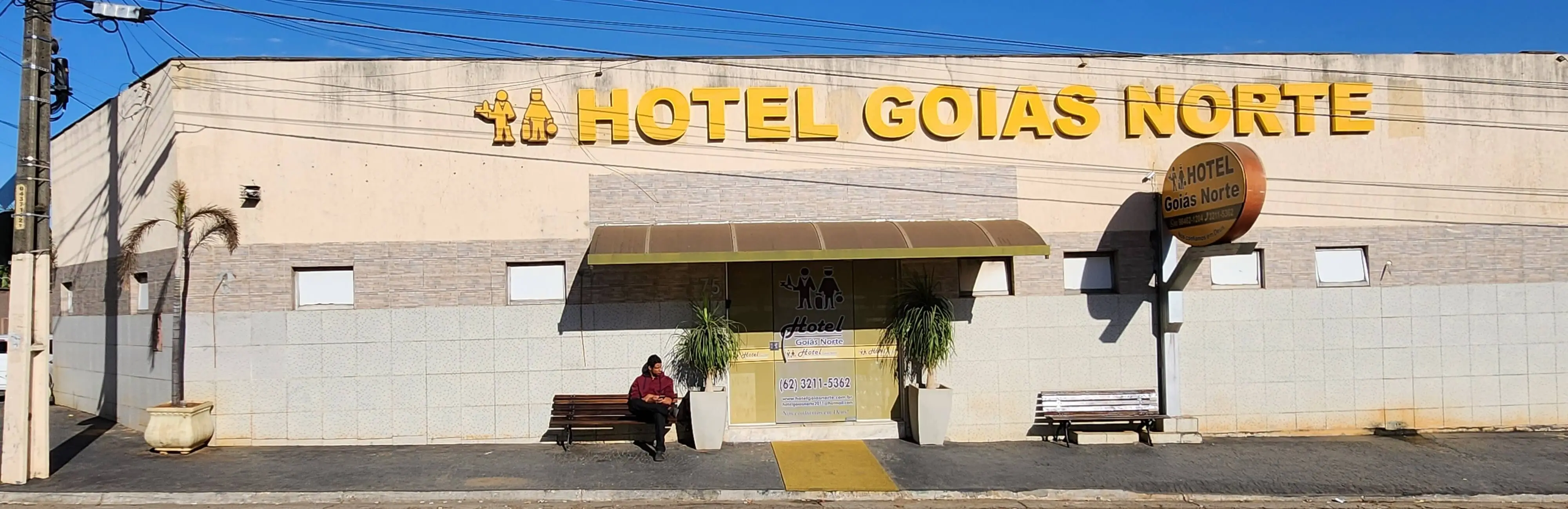 fachada do hotel na cor creme com vasos de planta na porta com tapete dourado que vai da porta até o meio fio da calçada.